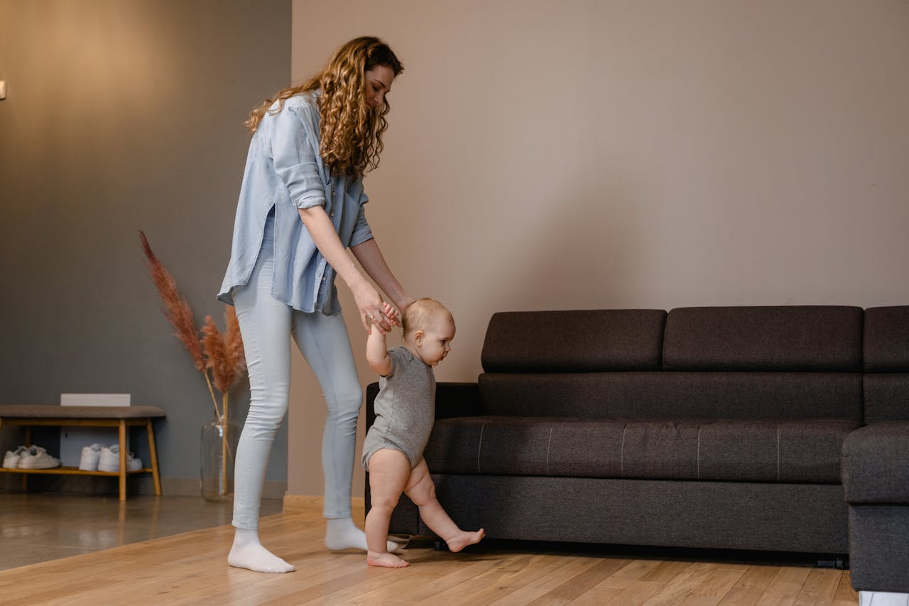 A mother helping a baby learn how to walk.