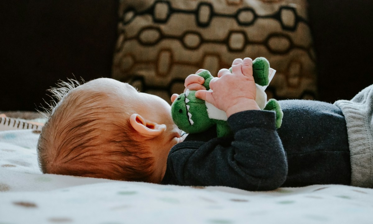 A baby lying down with their head turned away.