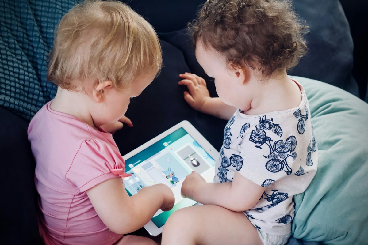 Two babies looking at the same screen.