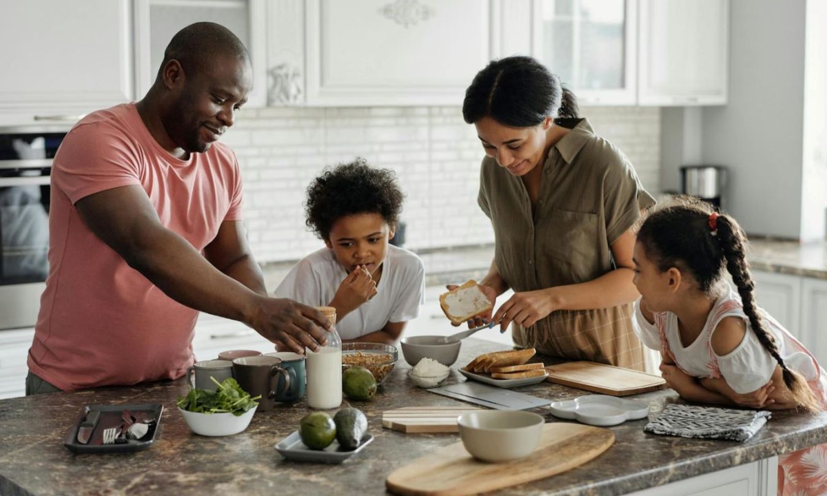 Parents and kids having fun in the kitchen making breakfast