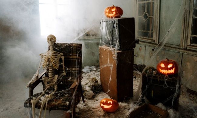 A creepy living room filled with cobwebs, a skeleton, and an old TV