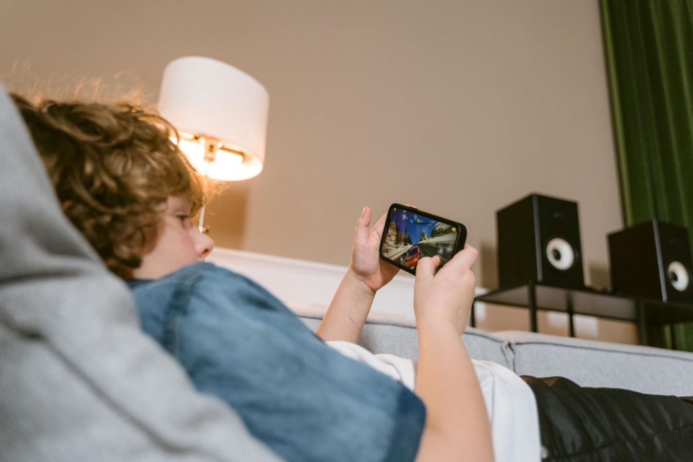 tween boy laying on couch on his cell phone