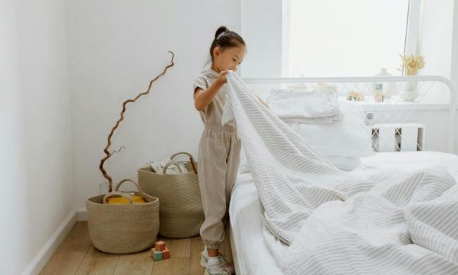 A tween cleaning by remaking the bed