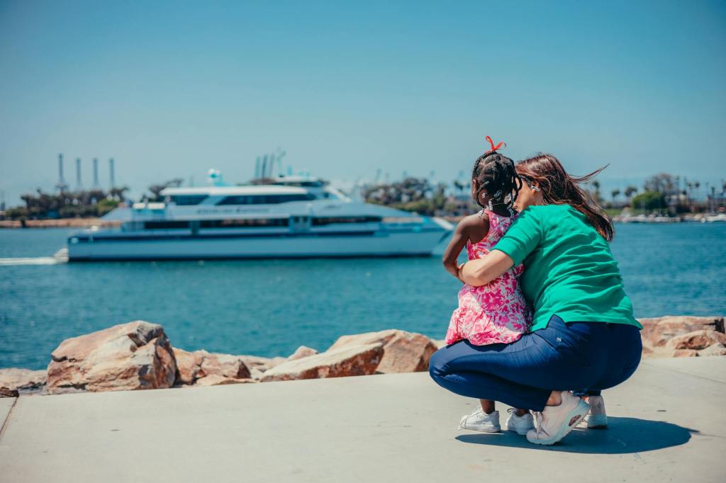 A parent and child looking at a cruise ship on the water.