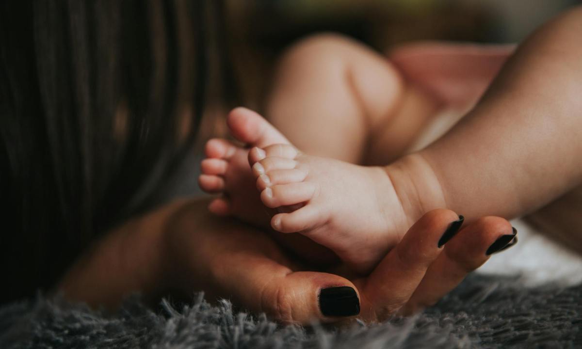 a mother holding a newborn baby's feet